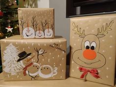 three wrapped presents sitting on top of a table next to a christmas tree with snowman and reindeer faces