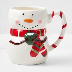 a snowman mug with a red and green scarf around it