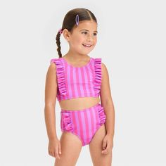 Add sweet style to your toddler's swimwear collection with the Ruffle Bikini Set from Cat & Jack™. This two-piece bikini set includes a sleeveless bikini top and a bikini bottom, both with a printed pattern and ruffle detailing along the sides for a stunning appeal. Tailored from recycled polyester fabric with spandex and full lining, this full-coverage bikini set offers comfort all the time, whether they're diving, playing in the sand or indulging in other activities. Best of all, they'll stay Toddlers Swimwear, Playing In The Sand, Striped Tankini, Solid Leggings, Swimwear Sets, Recycled Polyester Fabric, Tankini Set, Swimsuit Set, Swimsuit Shops