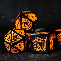 three orange and black dices sitting next to each other on a dark surface with lights in the background