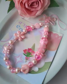 a pink flower and some pearls on a plate