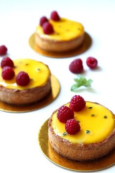 three small cakes with raspberries on them