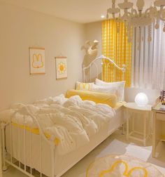 a white bed sitting in a bedroom next to a yellow and white curtained window