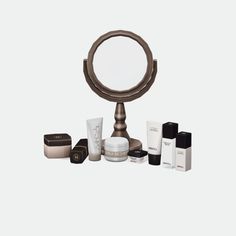 an assortment of skin care products sitting on a table next to a magnifying mirror