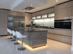 a modern kitchen with white chairs and an island in the middle is lit by recessed lighting