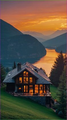 a large house sitting on top of a lush green hillside next to a lake at sunset