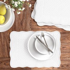 placemats, plates and silverware on a wooden table with flowers in a vase