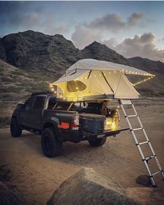 a truck with a tent attached to it parked on the side of a mountain at night