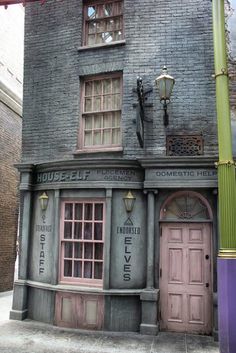 an old fashioned building with pink doors and windows on the outside, next to a street light