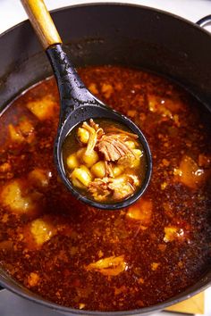 a ladle filled with stew and vegetables on top of a stove