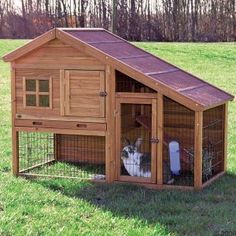 a small wooden house with a rabbit in it's cage on top of the grass