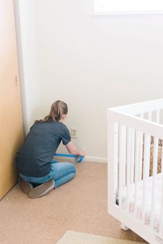 a woman sitting on the floor in front of a crib