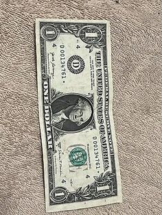 a one dollar bill sticking out of the side of a piece of paper