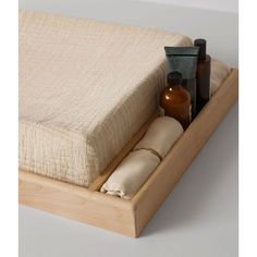 a wooden tray with bottles and soaps in it on top of a white surface