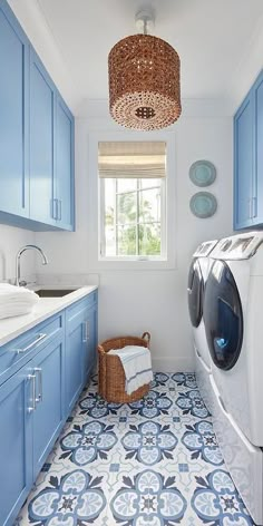 a washer and dryer in a blue and white bathroom with tile flooring