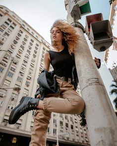 a woman standing on top of a pole next to a traffic light and tall buildings