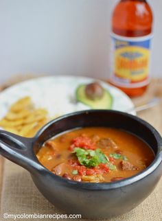 a bowl of soup with tortilla chips and a bottle of ketchup