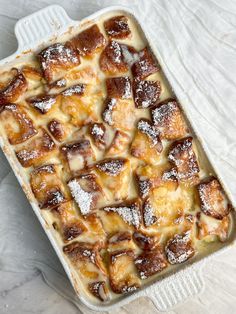 a casserole dish covered in powdered sugar and topped with cinnamon buns