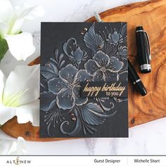 a birthday card with flowers on it and a pen next to it that says happy birthday to you