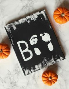 two small pumpkins sitting next to a black and white sign that says b is for baby