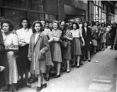 an old black and white photo of people lined up on the street