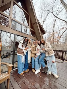 four women standing on a deck in front of a building with large windows and doors