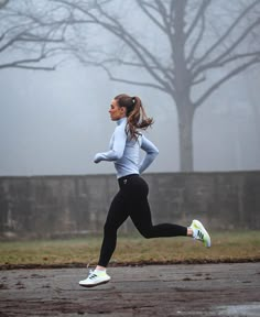 a woman running in the rain on a foggy day