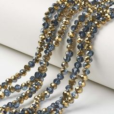 two strands of blue and gold glass beads on a white surface with one strand missing