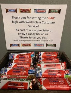 a wooden box filled with candy bar wrappers next to a sign that says thank you for setting the bar high with world class customer service