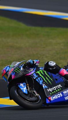 a person riding a motorcycle on a track with grass in the backgrouds