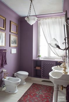 a bathroom with purple walls and pictures on the wall above the toilet, bidet and sink