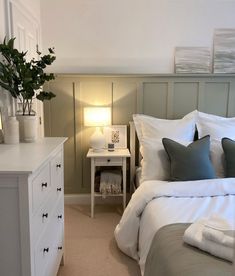 a white bed sitting next to a night stand with two lamps on top of it