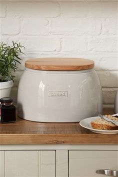 a large white pot sitting on top of a counter next to a plate with food