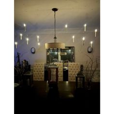 a dining room table and chairs with lights hanging from the ceiling