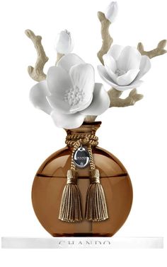 a brown vase with white flowers and tassels on it's sides, in front of a white background