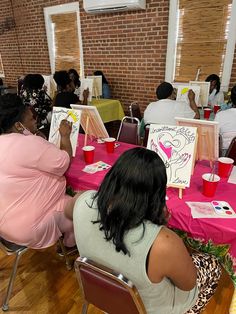 people sitting at tables with paintings on them