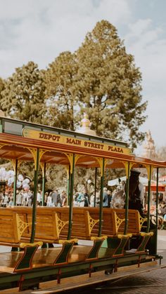 a trolley with wooden seats is on the street in front of some people and trees