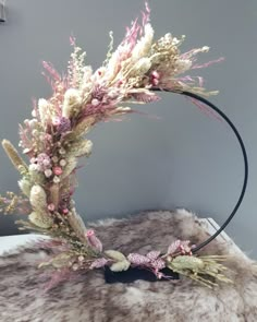 a wreath made out of dried flowers on top of a fur covered surface with a black wire