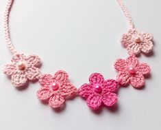 a crocheted necklace with pink flowers and pearls