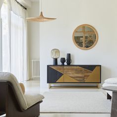 a living room with white walls and wooden furniture in it's centerpiece, along with a round mirror on the wall