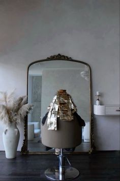 a mirror sitting on top of a wooden table next to a vase filled with feathers