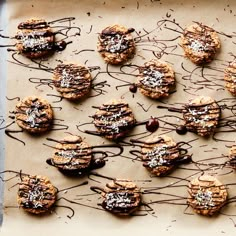 cookies with chocolate drizzle and sprinkles on a sheet of parchment paper