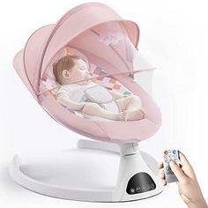 a person holding a remote control in front of a baby's cradle with a pink cover on it