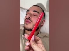 the man is sleeping with his eyes closed and holding a red pen in his hand