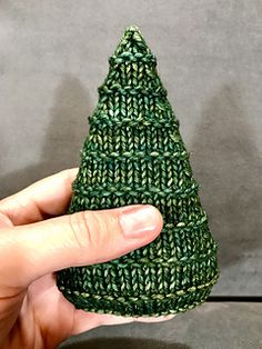 a knitted green christmas tree ornament being held by a person's hand