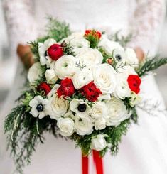 a bride holding a bouquet of white and red flowers