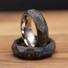 two wedding rings made out of rocks sitting on top of a wooden table