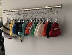 there are many sweaters hanging on the rack in this room, and one is wearing a hat