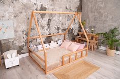 a wooden bed frame with pink pillows in a child's playroom area,