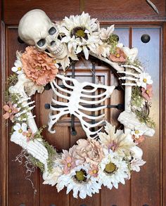 a wreath decorated with flowers and a skeleton on the front door for halloween or fall